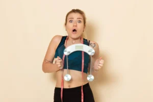 Mulher com rosto surpreso e segurando uma balança depois de medir metabolismo basal para emagrecer